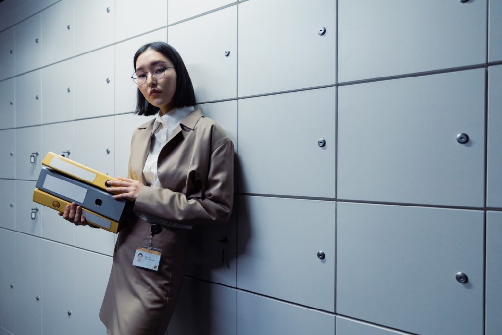 A lady office worker standing with files in a storage room