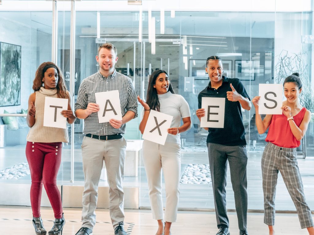 A group of people holding up letters to spell "Taxes"