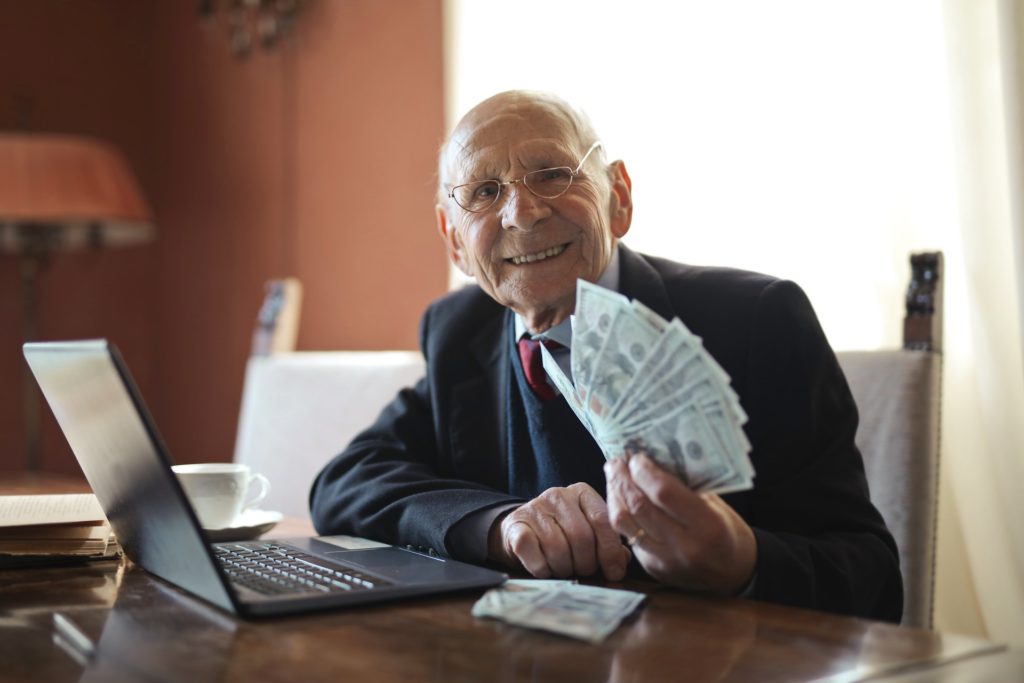 An elderly man with cash notes in his hand
