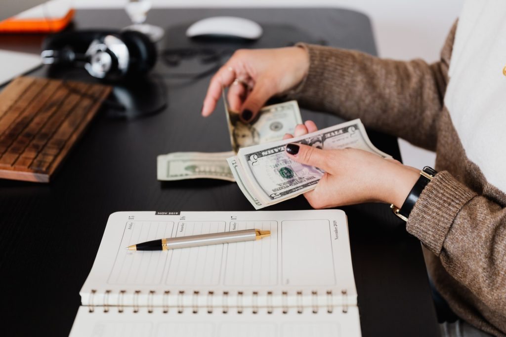 Accountant counting cash while making notes in a notebook