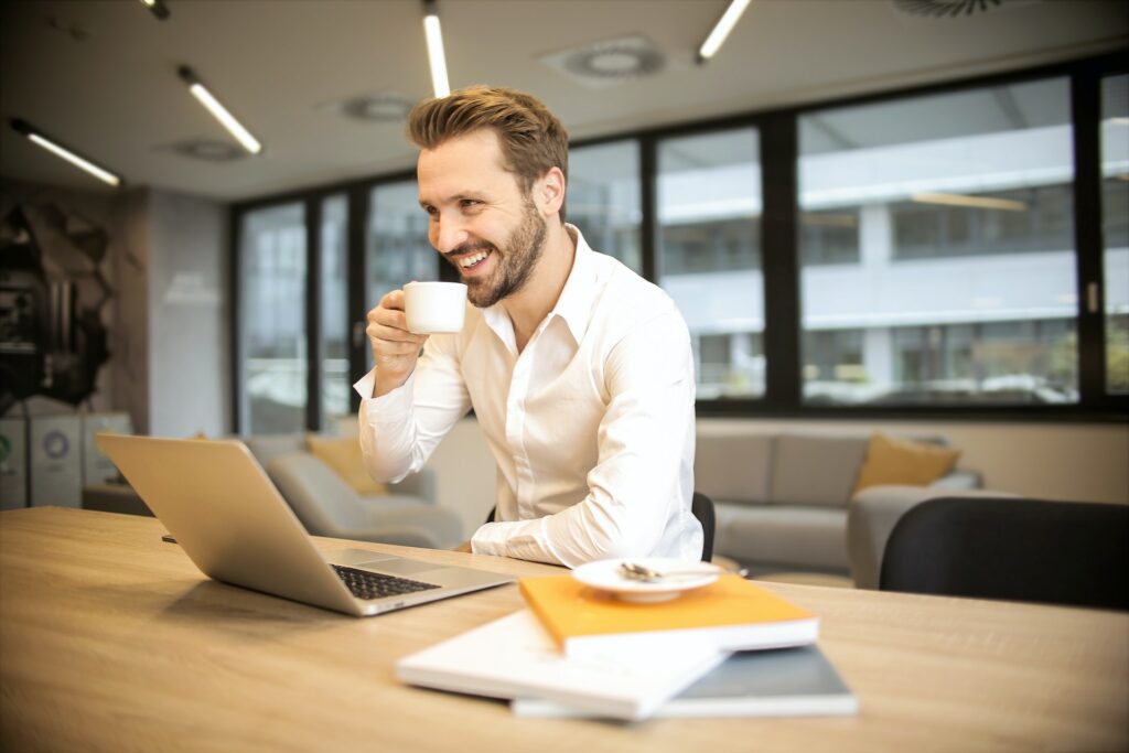 depth-of-field-photo-of-man-sitting-on-chair-while-holding-cup-in-front-of-table