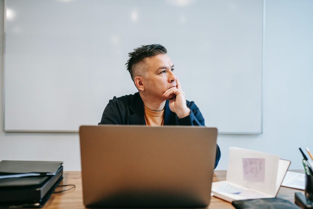 A small business owner thinking at his laptop