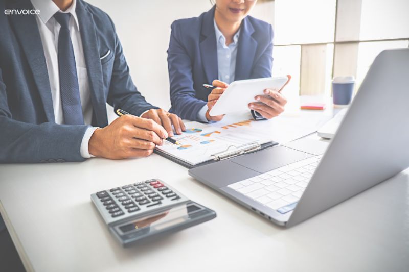 Business professionals reviewing financial data on a tablet and paper, analyzing the best accounts payable systems for efficiency