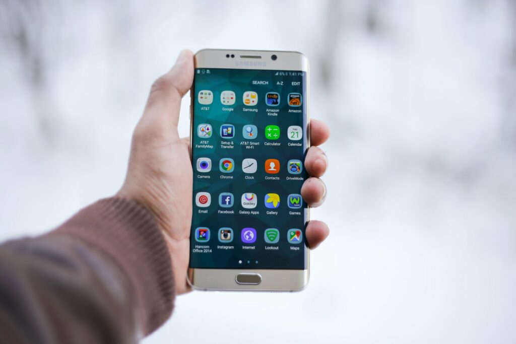 a close up photo of a man holding a mobile phone full of apps