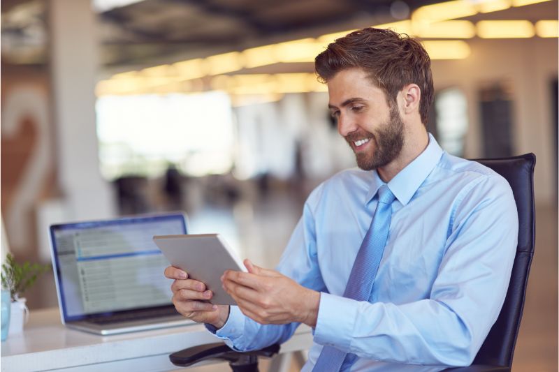 man smiling while holding a tablet