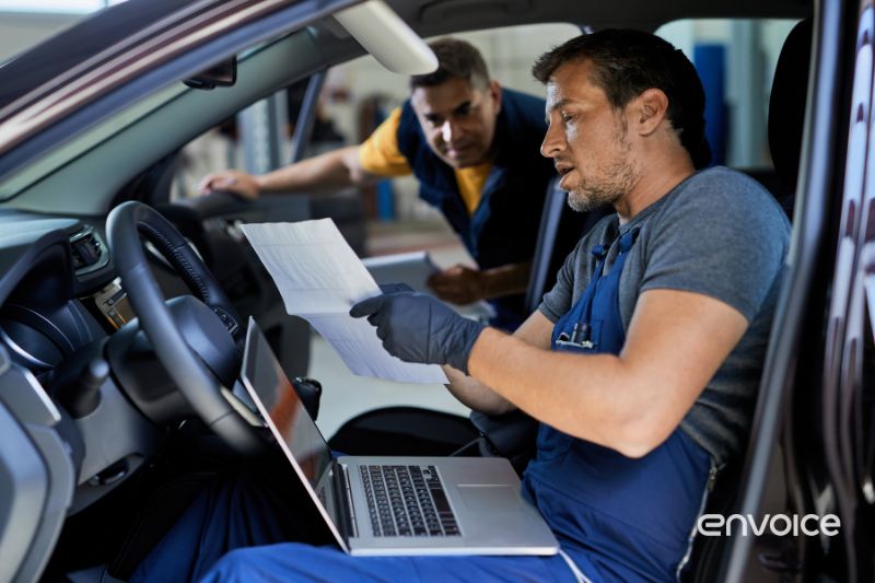 Two mechanics reviewing a physical receipts for a company’s automobile expenses.