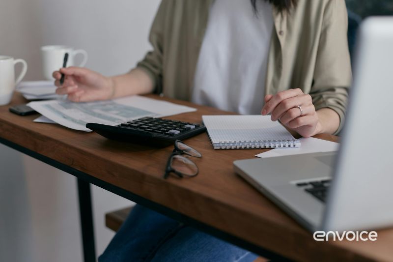 Person sitting at a desk using a calculator and reviewing business receipts manually for a small business