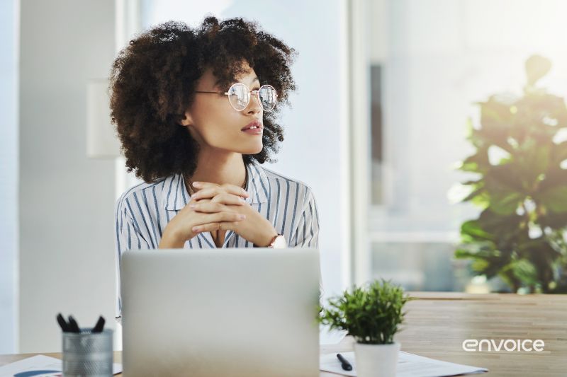 A thoughtful woman sits at a desk working on a laptop reflecting a business setting and contemplation of accounting software options.