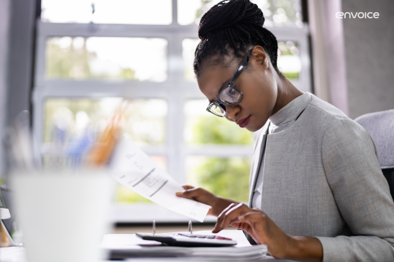 Accountant reviewing documents and using a calculator, representing efficient accounts payable management with cloud-based solutions