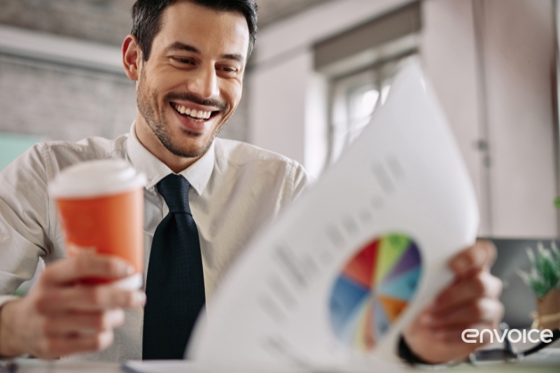 Smiling businessman reviewing a financial report in a modern office, showcasing the efficiency of expense management software for businesses.